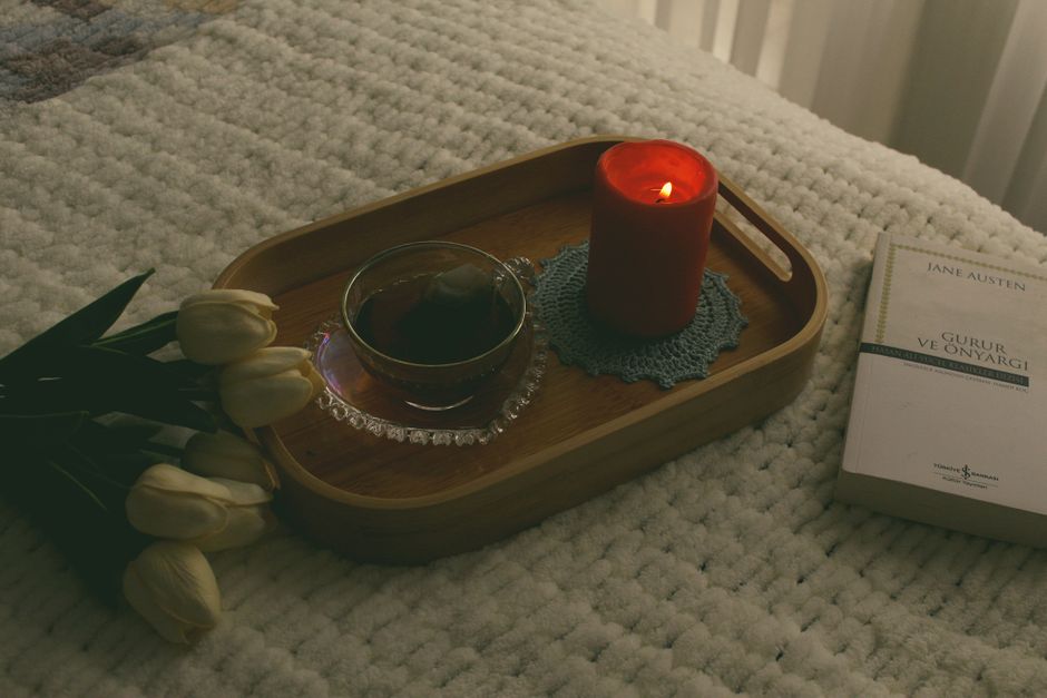 A calming bedside scene with a lit candle, tea, and a book for a perfect cozy ambiance.
